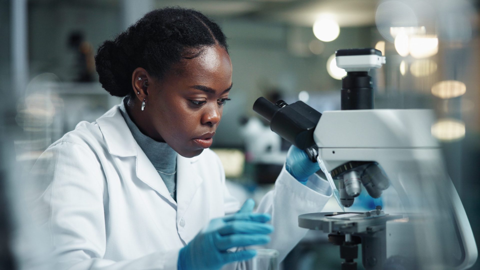 Black woman, scientist and microscope for lab research and medical study with pharma investigation. Virus, biotechnology and vaccine testing for health science with working healthcare professional.