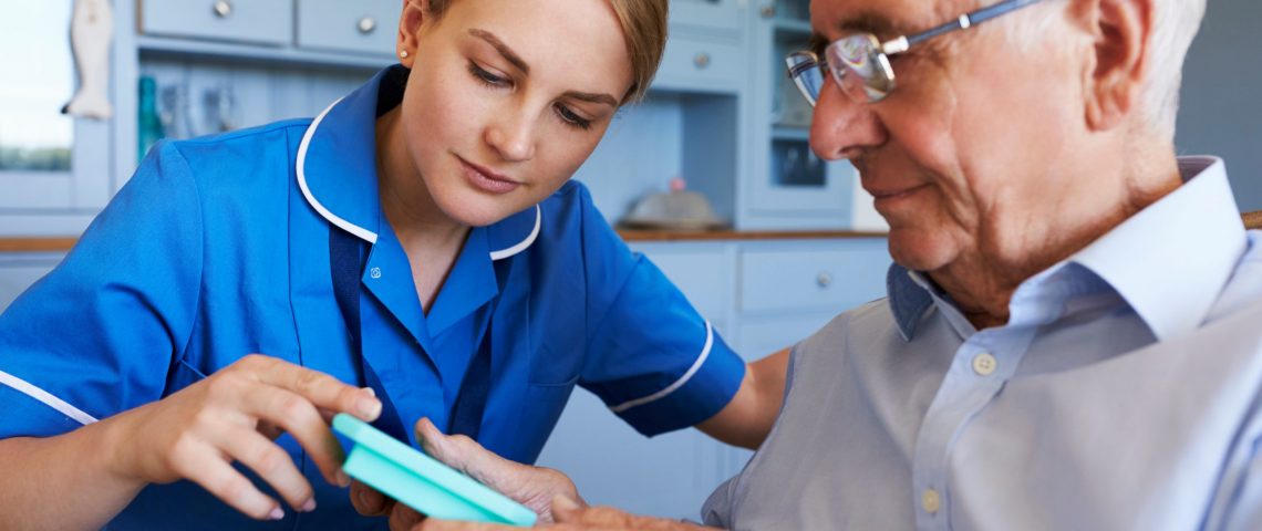 Nurse Helping Senior Man To Organize Medication On Home Visit
