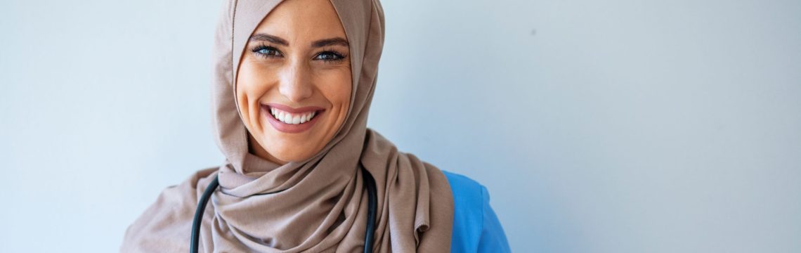 Confident female nurse. Confident Muslim female doctor standing with isolated gray. Closeup portrait of friendly, smiling confident muslim female doctor. Portrait of Muslim nurse with stethoscope