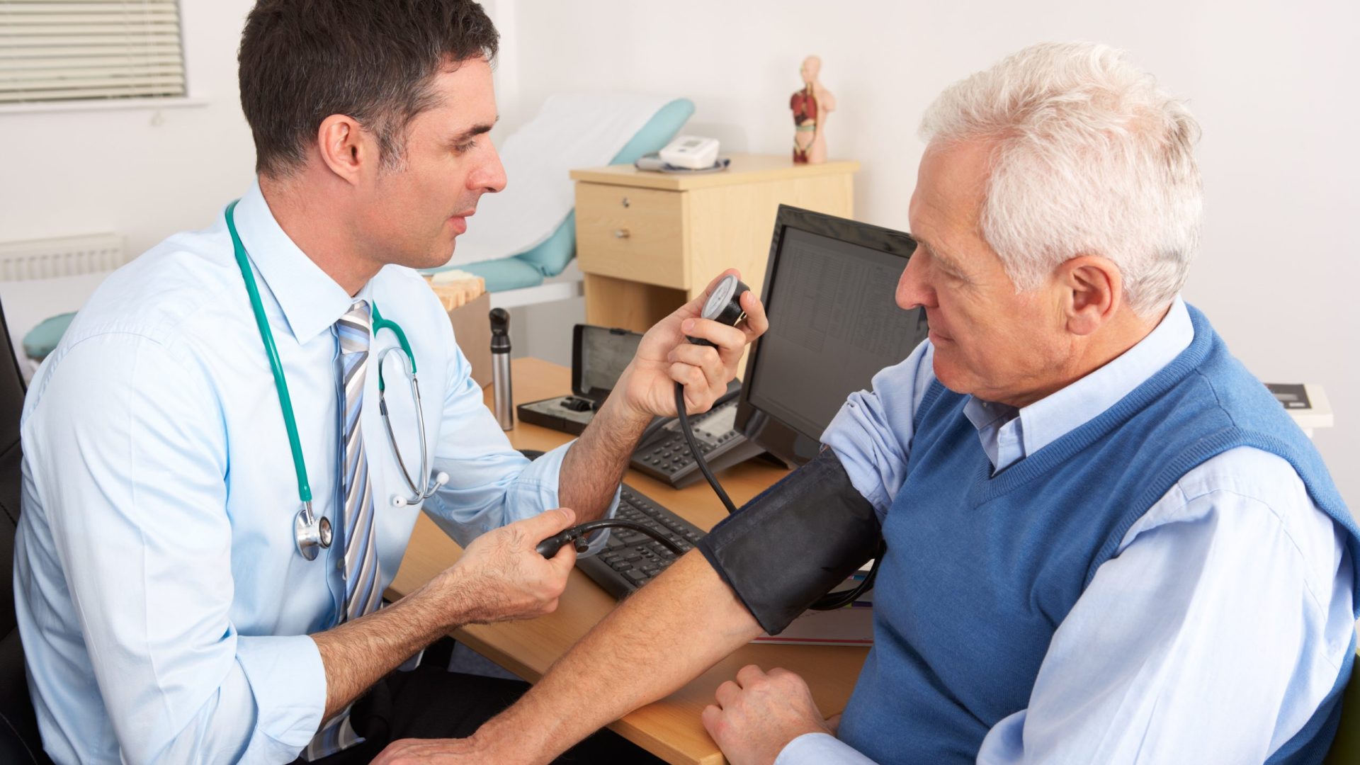British doctor taking senior man's blood pressure